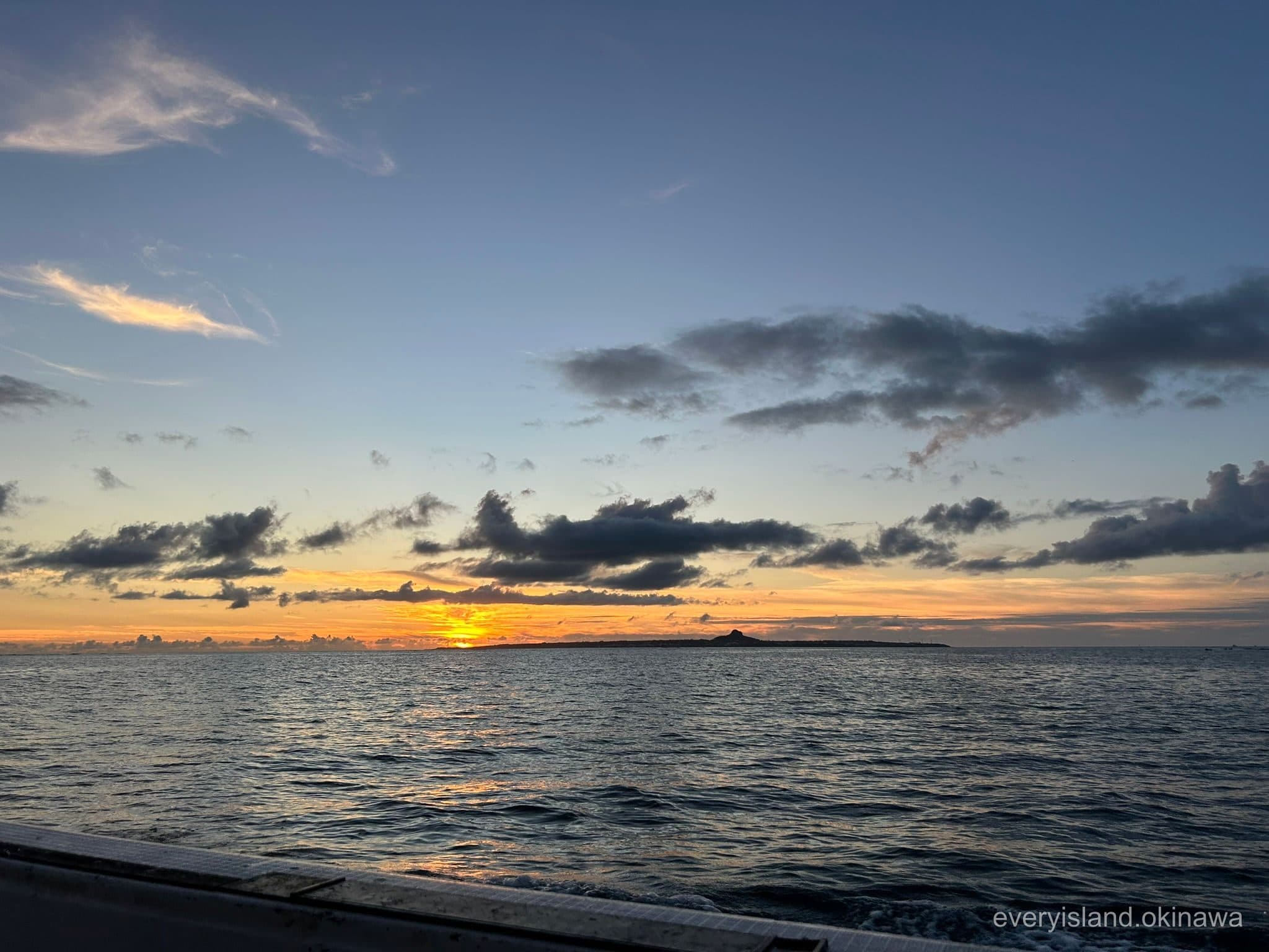 Sunset behind the silhouette of Ie Island seen from a boat off the Motobu coast